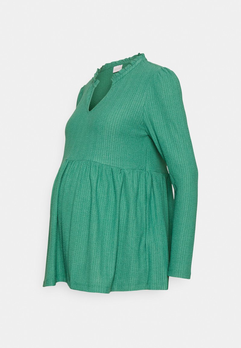 Top de maternidade verde, de mangas longas, com decote em V e colarinho com babados. Apresenta um tecido texturizado e um ajuste relaxado e evasé na barriga.