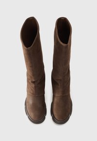 Brown leather knee-high boots with a textured finish, soft upper, and a chunky rubber sole. The design features a slouchy silhouette.