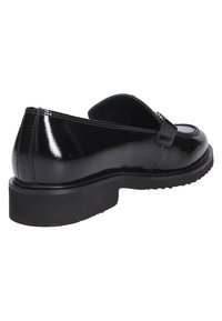 Schwarzer Lacklederschuh mit abgerundeter Spitze, flacher Sohle und einem dekorativen Riemen über dem Rist, der eine glatte, glänzende Textur aufweist.