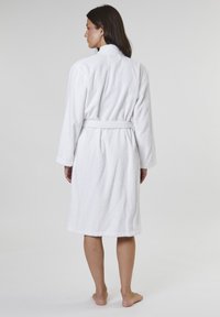 Hvid frotté badekåbe med sjalskrave, lange ærmer og et stofbælte; har en loopet struktur for sugeevne og komfort.