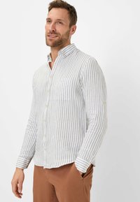 Button-up shirt in white with light gray vertical stripes, featuring a pointed collar, single chest pocket, and cuffed long sleeves.