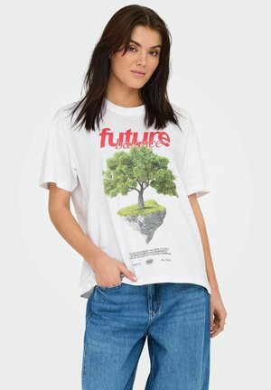 T-shirt en coton blanc avec un motif d'un arbre sur une île flottante. Le texte indique "équilibre futur" en rouge. Associé à un jean bleu.
