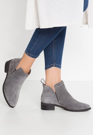 Szare zamszowe botki za kostkę z niskim, blokowym obcasem, bocznymi wycięciami i pętelką ułatwiającą zakładanie. Teksturowana powierzchnia i minimalistyczny design.