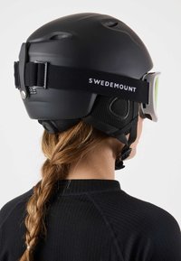 Zwarte skihabit met verstelbare kinband, ventilatieopeningen en geïntegreerde ski-bril. Heeft "SWEDEMOUNT" branding op de band.