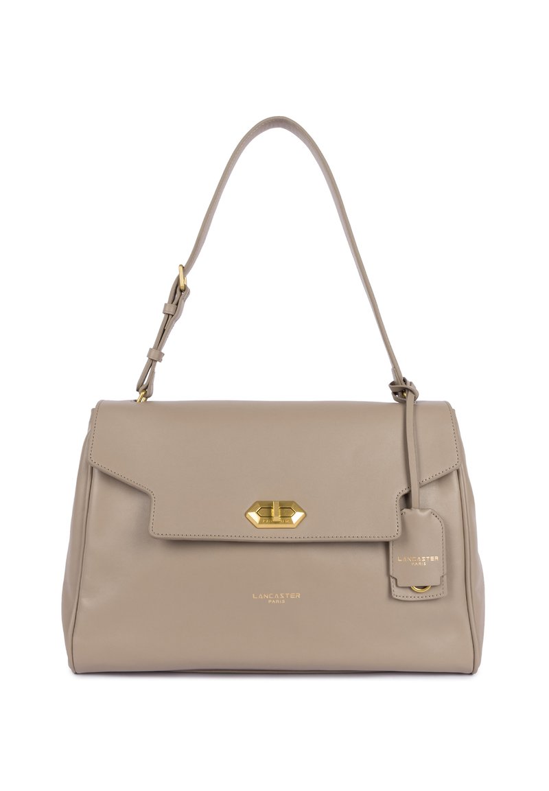Sac à main en cuir beige avec une forme structurée, accents en métal doré, rabat pliable et une étiquette amovible portant la marque "Lancaster."