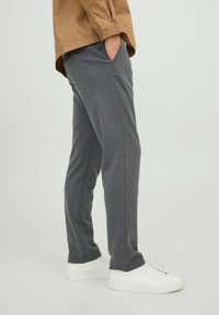 Graue Sweatpants aus weichem Stoff, mit Seitentaschen und tailliertem Schnitt, kombiniert mit weißen Sneakern für einen lässigen Look.
