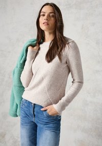 Hellbeige, geribbelter Pullover mit diagonalem Muster, langen Ärmeln und Rundhalsausschnitt, überlagert mit einer aquagrünen Fleecejacke.