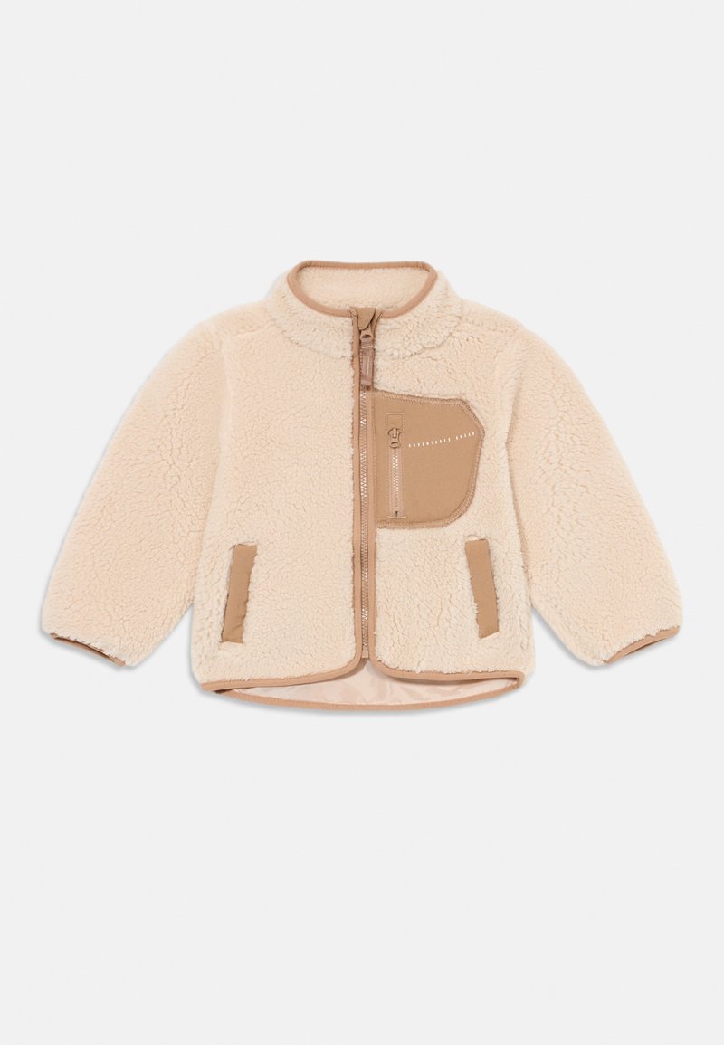 Chaqueta de forro polar beige con cierre frontal, cuello alto, gran bolsillo en el pecho y acentos en color marrón. Presenta una tela suave y texturizada, así como puños elásticos.