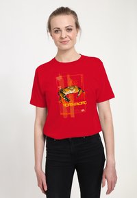 Rød bomulds T-shirt med et gult og sort krabbe grafik samt teksten "NORTH PACIFIC", sat mod en tekstureret baggrund.