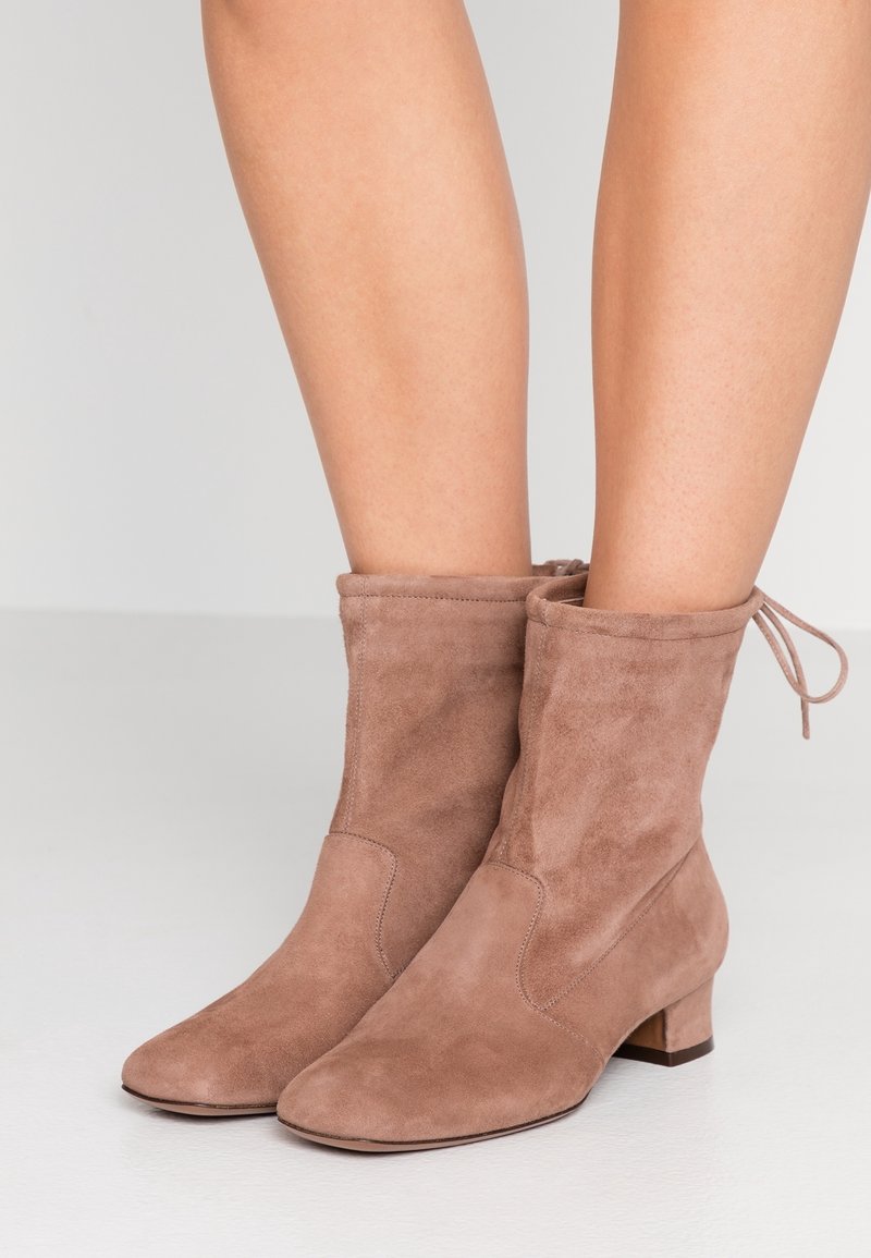 Mockasiner i ljust brunt med spetsig tå, en låg blockklack och en rynkad krage med dragsko-detaljer.