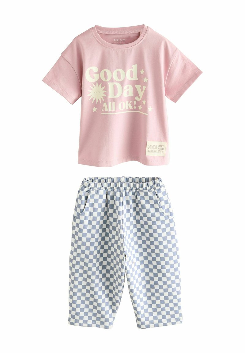 T-shirt rose avec l'impression "Bonne journée ! Tout va bien !" et une étiquette blanche, associée à un short �à imprimé vichy bleu et blanc. Matériel en coton doux.