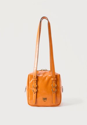 Orange skuldertaske i læder med dobbelte justerbare stropper, spænder i guld-tone og en lille metal logoemblem foran.