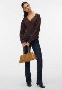 Bruine gebreide cardigan met een diepe V-hals en knoopsluiting, gecombineerd met donkere spijkerflared jeans en een tan rechthoekige handtas.