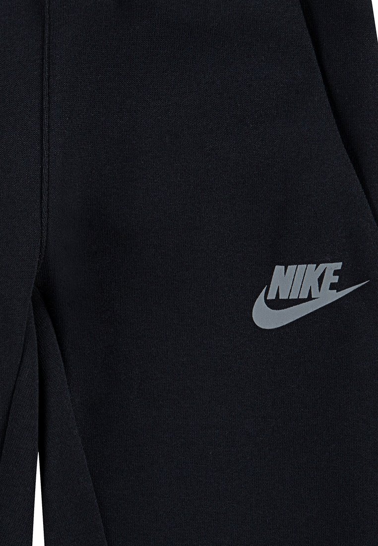 Pantalons de survêtement noirs en mélange de coton, avec une texture lisse, une coupe fuselée et un logo Nike réfléchissant gris sur la cuisse gauche.