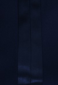 Granatowy materiał o gładkiej fakturze, z połyskującą satynową pionową linią biegnącą pośrodku, kontrastującą z matowym tłem.