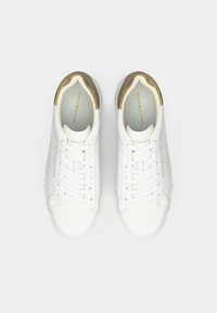 Baskets en cuir blanc avec une touche dorée le long du col, présentant un design classique à lacets et une marque sur les côtés.