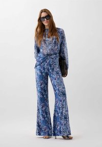 Conjunto azul con estampado que incluye una blusa larga y holgada de manga larga y pantalones acampanados. Hecho de una tela suave y fluida con varias tonalidades de azul.