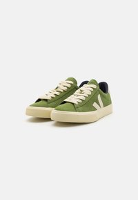 Green suede sneakers featuring beige laces, rubber soles, and a white logo accent. Includes a navy blue interior lining.