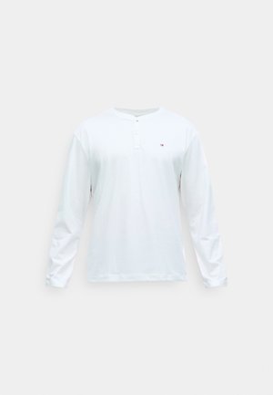 T-shirt blanc à manches longues en coton avec un col rond, doté d'une patte de boutonnage et d'un petit logo sur la poitrine. Design simple, texture lisse.