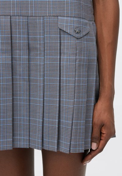 Riepa mini svārki ar zilu, brūnu un melnu rūtiņu rakstu, ar mazu sānu kabatu un teksturētu materiālu.