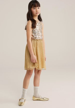 Zelta fliteru tanki tipa vakarkleita ar krokotu zelta svārku. Saskaņota ar zelta dzīvokļiem un baltām rakstainām zeķēm. Gluda tekstūra, vidēja garuma.