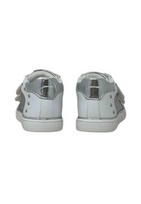 Un paio di sneakers bianche e argento per bambini con chiusure a strappo, viste da dietro su uno sfondo bianco.
