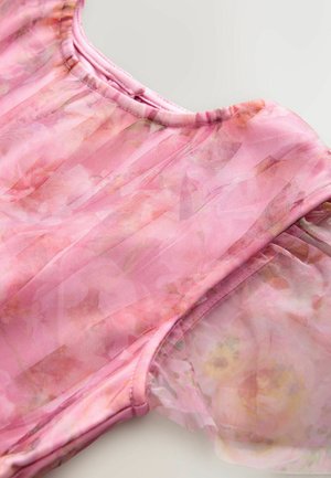 Robe fleurie rose avec des manches en tulle, présentant une texture douce et semi-transparente et un col froncé. Motif floral dans des nuances de rose plus claires et plus foncées.