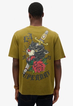 Oliven grøn T-shirt i bomuld med et stort grafisk design af en sort panter, sværd og røde roser på ryggen, samt iøjnefaldende tekstelementer.