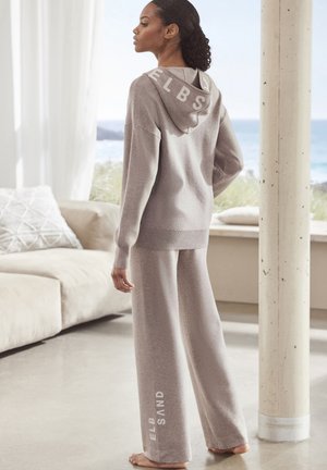 Lichtgrijze lounge-set met een hoodie en een wijdvallende broek. Kenmerken zijn een gestructureerde stof, logo-accenten en een ontspannen pasvorm.