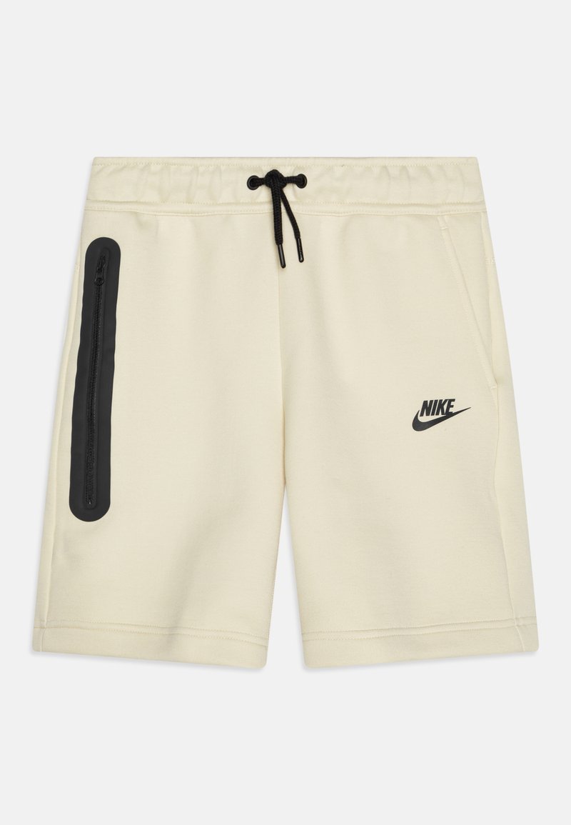 Krämfärgade Nike-shorts med elastiskt midjeband, svart dragsko och sidoficka med dragkedja. Har svart logotyp på framsidan.