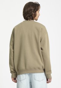 Sweatshirt vert olive à col rond avec manches longues, poignets et ourlet côtelés, fabriqué dans un matériau doux, présentant un design à coupe décontractée.