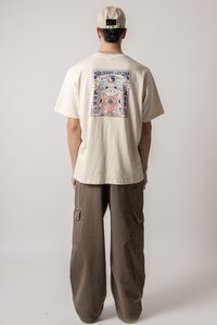 Beige t-shirt with a graphic print on the back, featuring a cat design and the text "Yakisoba Lovers." Paired with loose-fitting brown cargo pants.