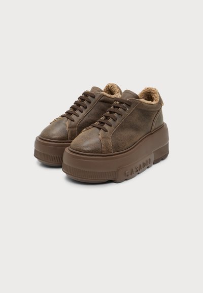 Paire de baskets à plateforme marron avec lacets sur le devant et doublure en polaire, semelles épaisses en caoutchouc avec le nom de la marque embossé sur le côté.