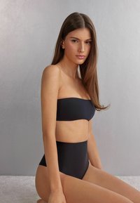 Sort bandeau bikini top parret med højtaljede bunde, glat tekstur, minimalistisk design og ingen synlige udsmykninger.