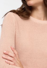 Jasnoróżowy, dziany sweter z okrągłym dekoltem i długimi rękawami, z teksturowanym wzorem i lekko luźnym krojem.