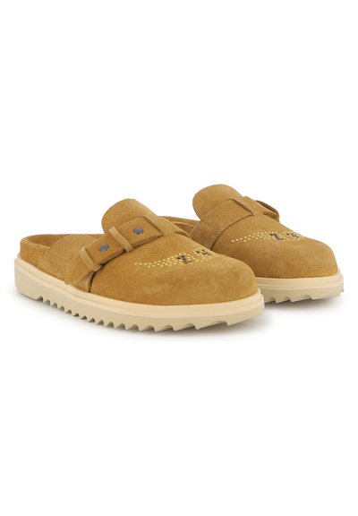 Καφέ γυναικεία παπούτσια από σουέντ χωρίς κορδόνια με διπλή λεπτομέρεια λουριού, διάτρητο σχέδιο στην επάνω πλευρά και μπεζ λαστιχένια σόλα με ανάγλυφο σχέδιο.