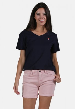 T-shirt en V bleu marine en tissu doux, associé à un short en denim rose clair. Doté d'un logo simple sur la poitrine et d'une coupe classique.
