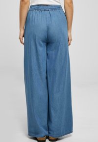 Hellblaue Denim-Hose mit weitem Bein und elastischem Bund, mit glatter Textur und lockerem Sitz, geeignet für die Freizeit.