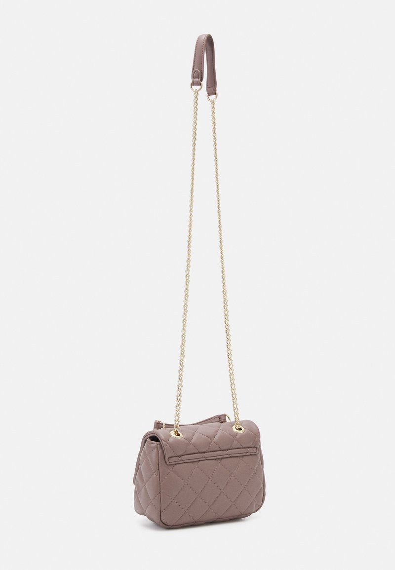 Sac à main en simili cuir matelassé de couleur mauve, doté d'une bandoulière en chaîne dorée et d'une anse supérieure. Comprend une poche zippée à l'arrière pour un espace de rangement supplémentaire.