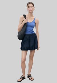 Light blue sleeveless top, dark denim skirt, black woven shoulder bag, and black sandals. Classic casual outfit with a relaxed fit.