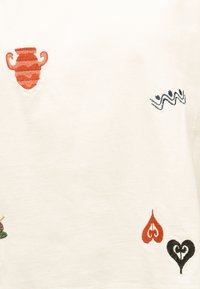 Μπεζ ύφασμα με μικρά κεντημένα σχέδια, όπως ένα κόκκινο βάζο, καρδιές σε μαύρο και κόκκινο χρώμα και μαύρες κυματιστές γραμμές.