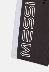 Shorts mit einem dunkelgrauen Körper und einem weißen Seiteneinsatz, der große weiße Schriftzüge zeigt. Hergestellt aus einem weichen Stoff mit glatter Textur.