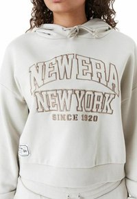 Felpa cortesti grigia chiara con una grafica bianca e beige. Presenta un cappuccio con cordoncino, orlo a coste e etichetta laterale. Realizzata in una miscela di cotone.