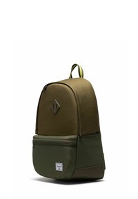 Sac à dos en tissu vert avec un dessus arrondi, un accent en forme de losange à l'avant et une poche avant. Dispose d'une poignée de transport et d'une sangle contrastante.