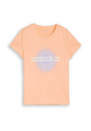 Peach-colored short-sleeve T-shirt with a round neck and "BREATH IN" text over a subtle blue circular gradient on the front.