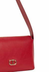 Borsa a tracolla rossa in pelle con forma piatta, texture liscia, dettagli in metallo dorato e tracolla regolabile. Chiusura con zip nella parte superiore.