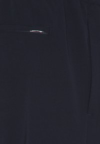 Marina byxor med slät front, en dragkedjeficka och mjuk tygkänsla. Minimal synlig sömnad och skräddarsydd design.