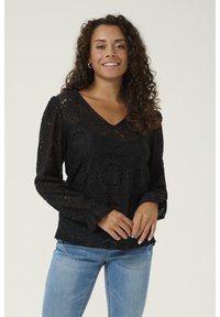 Blusa nera in pizzo con scollatura a V, maniche lunghe a sbuffo e motivi floreali. Il tessuto ha un aspetto strutturato con dettagli intricati.