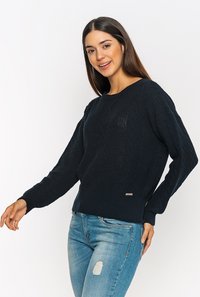 Dunkelblauer Strickpullover mit strukturiertem Kabelmuster, rundem Ausschnitt und langen Ärmeln; verfügt über einen kleinen metallischen Logoakzent am Saum.