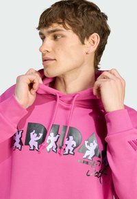 Lys pink hoodie med snor, med sorte og hvide grafiske designs på fronten. Glat stof og ribbede manchetter.